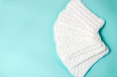 Kadınsı hijyen malzemelerinin düzlüğü. Turkuaz arka plandaki kritik kadın günlerinin ayrıntıları. Kadınlar için contalar, sağlık