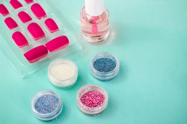 Turkuaz arka planda bir manikür dairesi. Oje, sim, jöle ve takma tırnaklar, tırnak uçları.