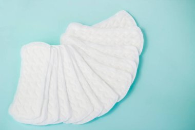 Kadınsı hijyen malzemelerinin düzlüğü. Turkuaz arka plandaki kritik kadın günlerinin ayrıntıları. Kadınlar için contalar, sağlık