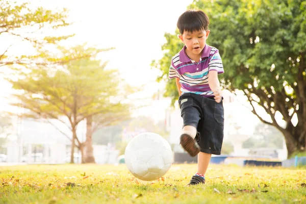 Boy learning kick ball at the park in the evening