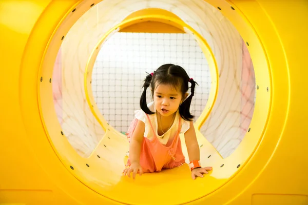 Küçük bir gülümseme kız playgrou sarı tünel dışarı sürünüyor