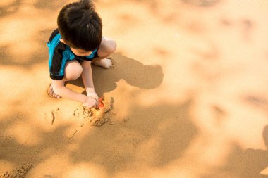 Bir yüzme elbiseli oturma plaj ve iskambil kum çocuktur 