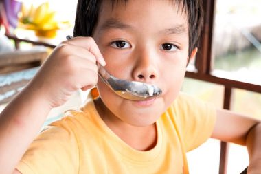 Aç bir çocuk, oturmak için ahşap masa tatlı r de yiyin.