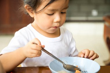 Eat bu b, şehriye için kız tahta masada oturuyor