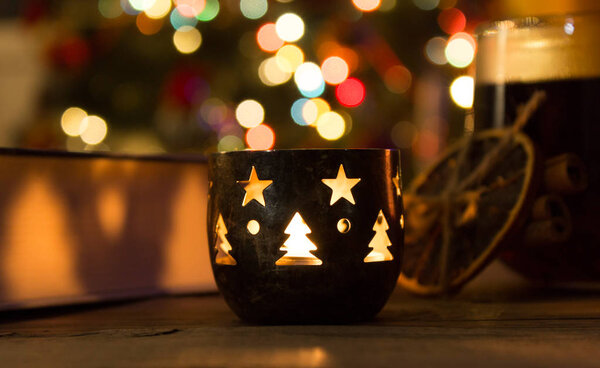 beautiful candle on a wooden table with a cup of tea and christm