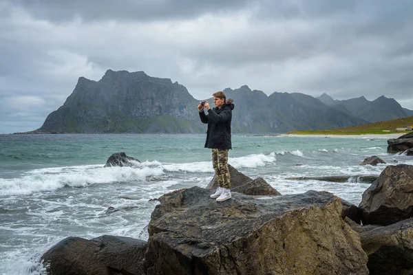 Niño toma fotos en un teléfono móvil en una playa en el norte de Noruega — Foto de Stock
