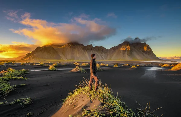 Senderista disfrutando de la puesta de sol en Vestrahorn y su playa de arena negra en Islandia — Foto de Stock