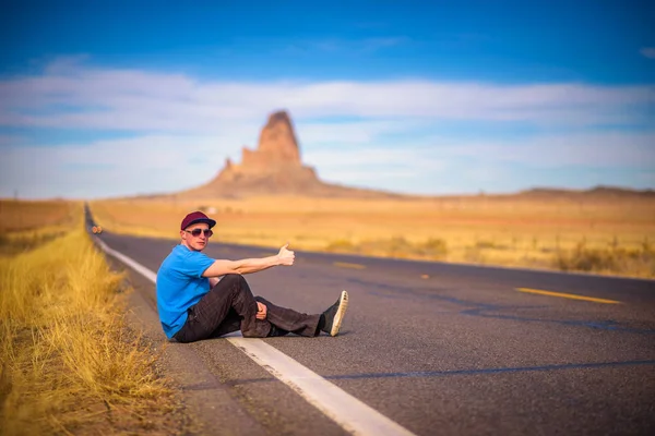 Tired hitch-hiker sitting on a road