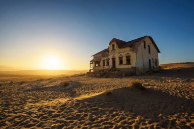 Kolmanskop hayalet kasabası Namibya 'da terk edilmiş bir evin üzerinde gün doğumu