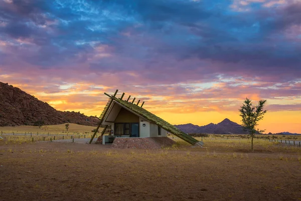 Nascer do sol acima de uma pequena cabana em uma pousada no deserto perto de Sossusvlei, na Namíbia — Fotografia de Stock