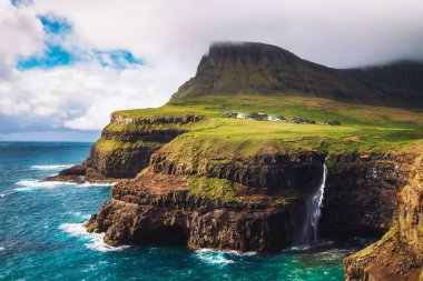 Gasadalur köyü ve şelalesi güçlü rüzgar altında, Faroe Adaları, Danimarka