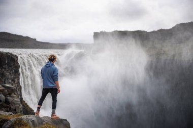 İzlanda 'da Dettifoss şelalesinin kenarında duran yürüyüşçü.
