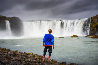 İzlanda 'daki Godafoss şelalesinde duran yürüyüşçü.