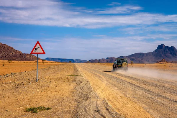 Αυτοκίνητο που περνά μια προειδοποιητική πινακίδα καμηλοπαρδάλεις στην έρημο της Ναμίμπια — Φωτογραφία Αρχείου