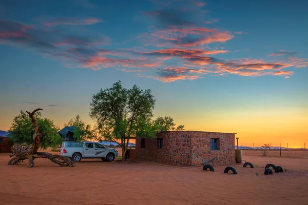 Pôr do sol em um acampamento no deserto na Namíbia com um carro 4x4 pickup com uma barraca do telhado — Fotografia de Stock