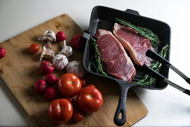 Taze sığır eti. Tavada biftek. Et ve sebze. Mermer biftek. Biberiye ve yağ..