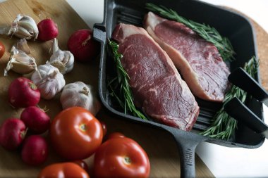 Taze sığır eti. Tavada biftek. Et ve sebze. Mermer biftek. Biberiye ve yağ..