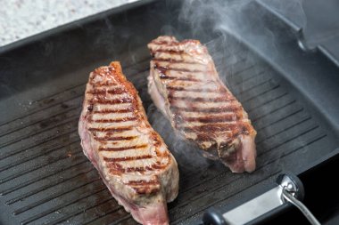 Et parçaları kızartma tavasında pişirilir. Zengin ve sulu biftekler. Et pişiriyorum..