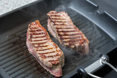 Et parçaları kızartma tavasında pişirilir. Zengin ve sulu biftekler. Et pişiriyorum..