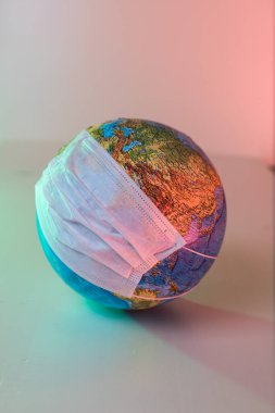 Dünya gezegeninin küresi. Pandemik koronavirüs. Tıbbi maskeli bir gezegen. COVID-19.