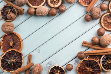 Çerçeve şeklinde ahşap bir masanın üzerindeki kahve çekirdekleri. Tarçın çubukları ve kurutulmuş meyve. Mesaj için yer var. Masada fındık var. turkuaz renk tahtaları.