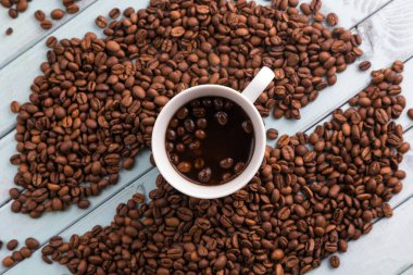 Kahve çekirdekleri ahşap bir masaya dökülür. Kahve fincanı turkuaz masada. Kahveyle hayat.