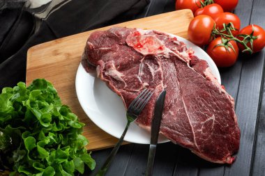 Koyu arkaplanda yemek malzemeleri olan taze et. Tabakta sulu biftek. Et ve sebze. Dengeli diyet.