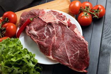 Koyu arkaplanda yemek malzemeleri olan taze et. Tabakta sulu biftek. Et ve sebze. Dengeli diyet.