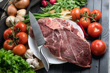 Tahta doğrama tahtasının üzerinde taze seçilmiş sığır eti var. Taze et ve sebzeler sebzeli sulu biftek. Uygun, dengeli beslenme.