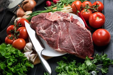 Tahta doğrama tahtasının üzerinde taze seçilmiş sığır eti var. Taze et ve sebzeler sebzeli sulu biftek. Uygun, dengeli beslenme.