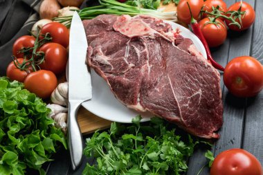 Tahta doğrama tahtasının üzerinde taze seçilmiş sığır eti var. Taze et ve sebzeler sebzeli sulu biftek. Uygun, dengeli beslenme.