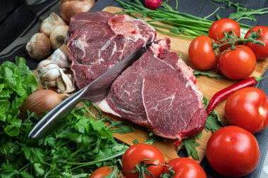 Tahta doğrama tahtasının üzerinde taze seçilmiş sığır eti var. Taze et ve sebzeler sebzeli sulu biftek. Uygun, dengeli beslenme.