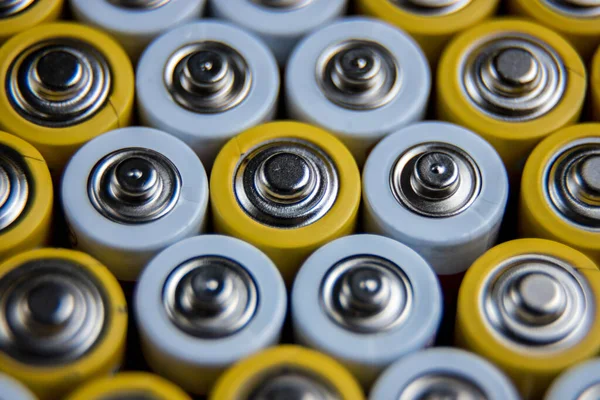 A large number of old AA batteries. The batteries are laid out in a square shape. Batteries form a beautiful background. A variety of power sources. Pattern of batteries laid out in a row.