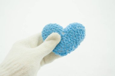 Mavi örülmüş kalp, beyaz bir eldivenin içinde kardan bir arka planda. Sevgililer Günü 'nün kutlu olması fikri.