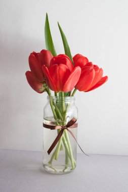 Açık arkaplanda bir buket kırmızı lale çiçeği. Bahar tatili kartı.