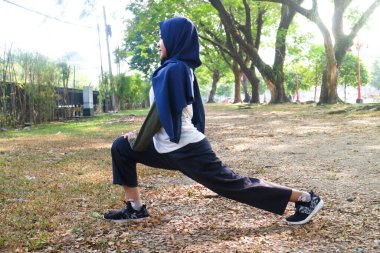 Bir tesettürlü kadın egzersizden önce ısınır.