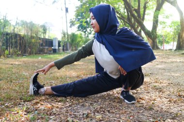 Bir tesettürlü kadın egzersizden önce ısınır.