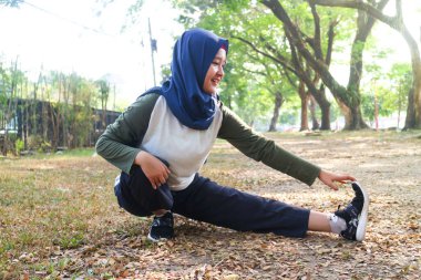 Bir tesettürlü kadın egzersizden önce ısınır.