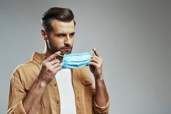 Giovane Uomo Assumendo Maschera Protettiva Guardando Lontano Mentre Piedi Contro — Foto Stock