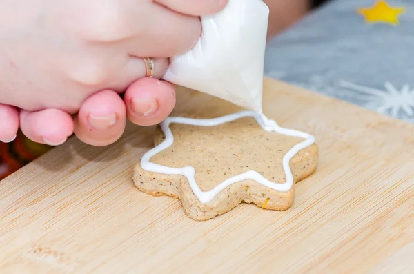 Mujer joven decora galletas de Navidad — Foto de Stock