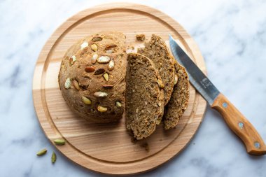 Tahtasında kabak çekirdeği olan ev yapımı ekmek. Masada yuvarlak ekmek var. Fırında fırın. Taze çörek. Tahtada dilimlenmiş ekmek.