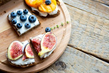 Tahtada ev yapımı ekmek. Böğürtlen, incir ve peynirli şeftali. Vejetaryen yemeği. Düzgün beslenme. Atıştırmalık Tahtada dilimlenmiş ekmek.