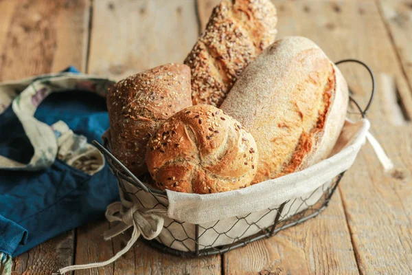 Bread in a basket on a black background. Assorted baking in a metal basket. Place for recipe and text. Background with rolling pin and flour. Rye bread and baguette with seeds. Buckwheat bread