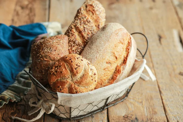 Bread in a basket on a black background. Assorted baking in a metal basket. Place for recipe and text. Background with rolling pin and flour. Rye bread and baguette with seeds. Buckwheat bread