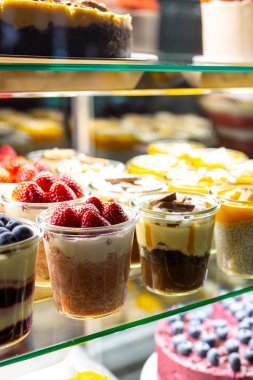 Pencerede çilekli ve çilekli tatlılar var. Bardakta Snickers tatlısı. Dükkanda peynirli kek, hamur işi ve kurabiye satan bir dükkan. Tatil için dolapta şeker var. Pasta.