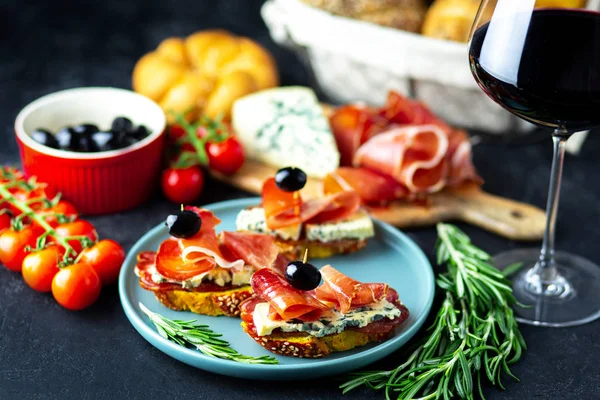 Table appetizers with Italian antipasto appetizers. Bruschetta or authentic traditional spanish tapas set, cheese board. Wine snack on a wooden board. Cheese, jamon, prosciutto and cherry tomatoes.