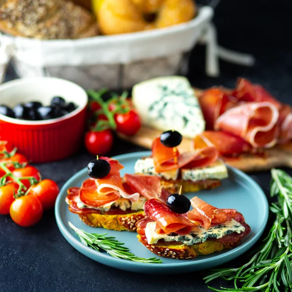 Table appetizers with Italian antipasto appetizers. Bruschetta or authentic traditional spanish tapas set, cheese board. Wine snack on a wooden board. Cheese, jamon, prosciutto and cherry tomatoes.