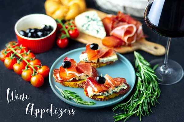 Table appetizers with Italian antipasto appetizers. Bruschetta or authentic traditional spanish tapas set, cheese board. Wine snack on a wooden board. Cheese, jamon, prosciutto and cherry tomatoes.
