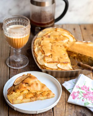 Kahveli ahşap bir masada Charlotte Pie. Dondurmalı turta. Bir kepçe dondurmalı elmalı turta ve tabakta karamel sosu, sonbaharda pişirme konsepti. Güzel bir parça meyveli turta.