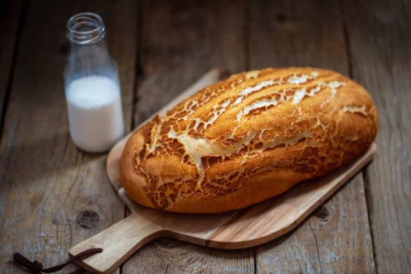 White bread on a wooden board. Bread in the bakery has just come from the oven. Fresh baking on a wooden table. Hot pastries. Breakfast. Bread and milk